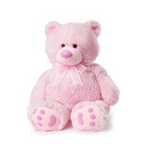 A pink teddy bear with bow tie sitting on white background.