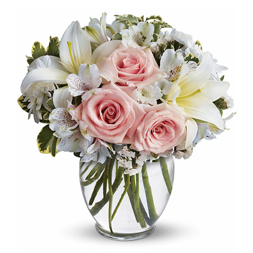 A vase filled with pink roses and white flowers.