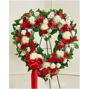 A heart shaped wreath of red and white flowers.
