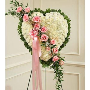 A heart shaped funeral arrangement with pink roses.