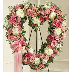 A heart shaped wreath of pink and white flowers.