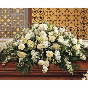 A casket with white flowers on top of it.