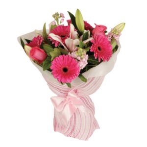 A bouquet of flowers wrapped in paper with pink ribbon.