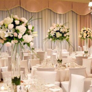 A room with many tables and chairs decorated in white.