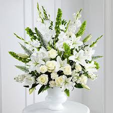 A white vase filled with flowers on top of a table.
