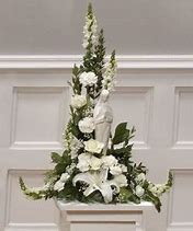 A white flower arrangement with a statue of jesus.